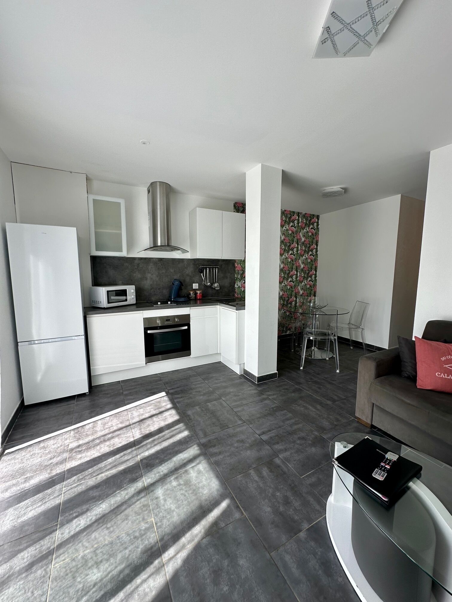 A modern kitchen with white cabinets, a microwave, and a stove. There is a dining area with a table and chairs.