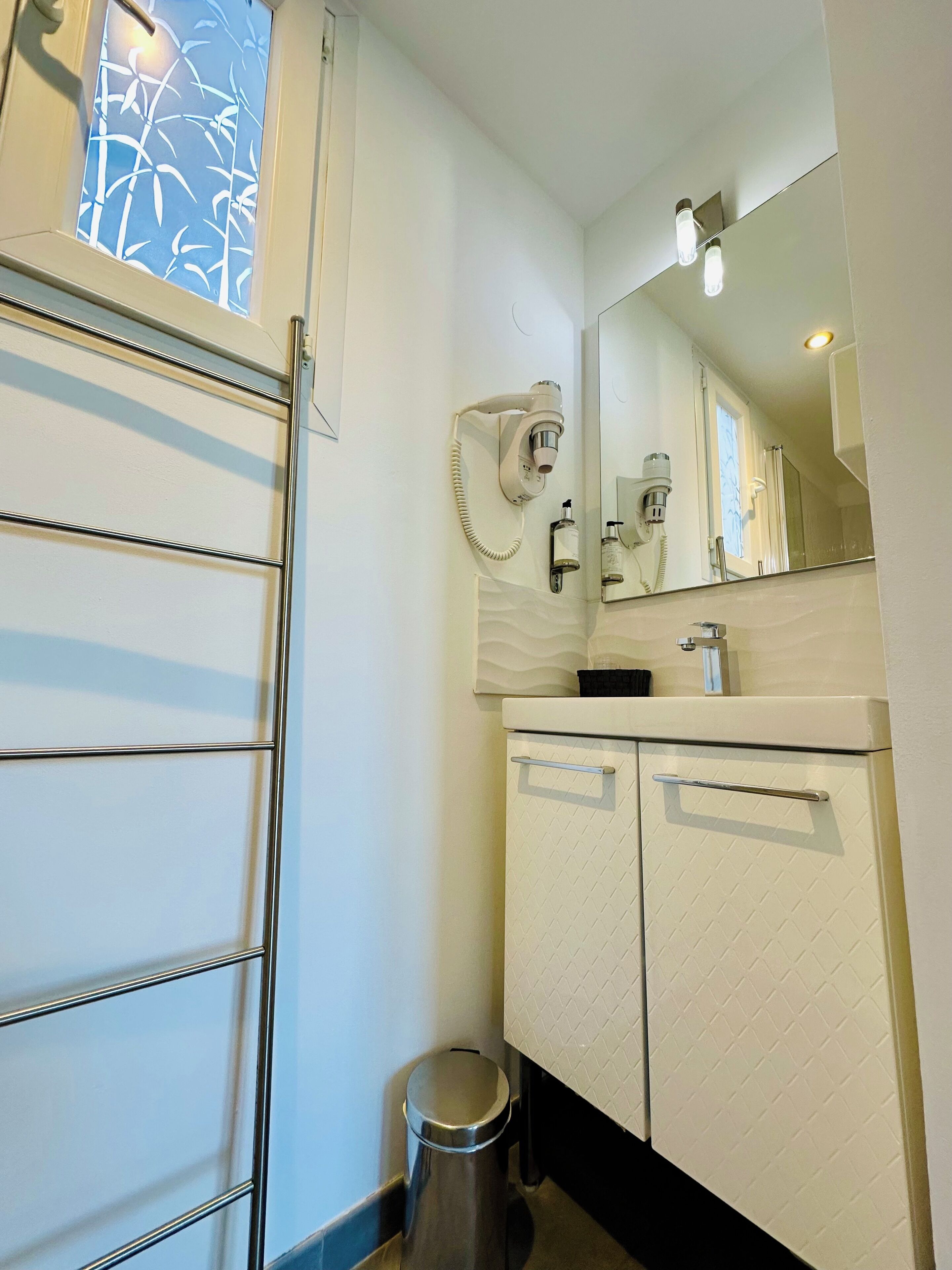Un baño con toallero, espejo, lavabo e inodoro.