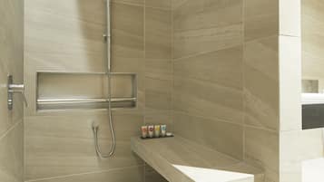 A modern shower with a handheld showerhead, a built-in shelf, and a wall-mounted towel rack.