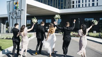 A group of people in formal attire outside a building with a sign reading "HYATT PLACE".