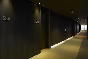 Corredor com paredes de madeira escura e números iluminados 524 e 523.