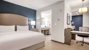 Een hotelkamer met een groot bed, een bureau, een stoel, een lamp en een spiegel.