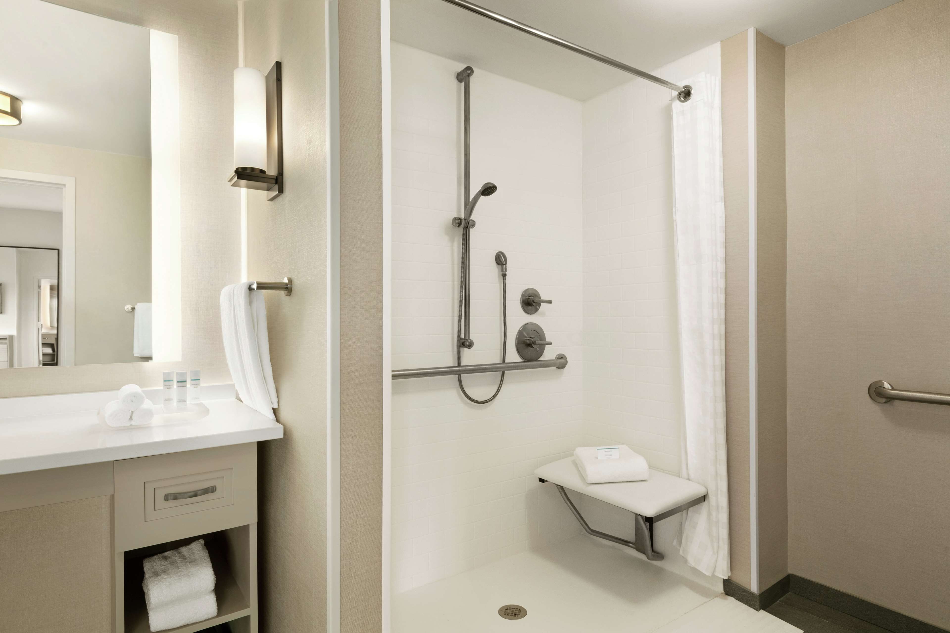 Ein modernes Badezimmer mit Dusche, Waschtisch inklusive Spiegel und einem Handtuchhalter.