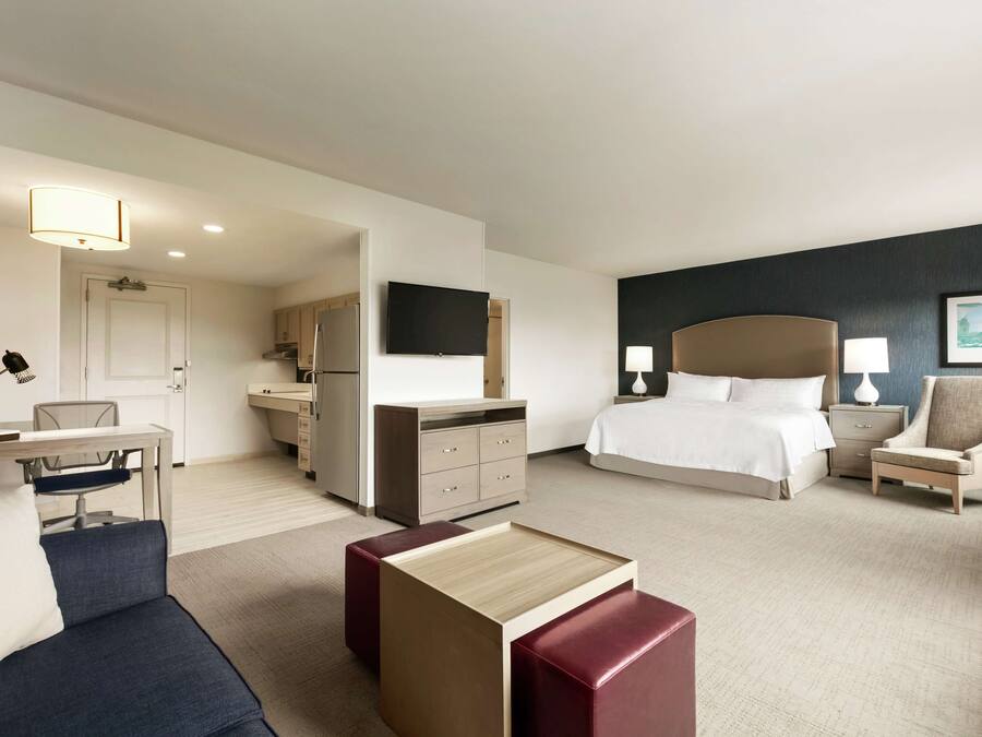 Ein Hotelzimmer mit Bett, Schreibtisch, Stuhl, Fernseher und einem kleinen Tisch.