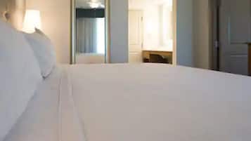 Habitación de hotel con una cama grande, un espejo y una puerta que da al baño.