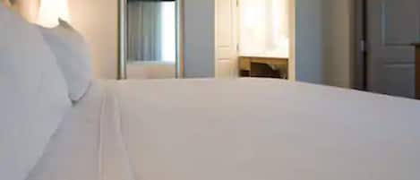 Een hotelkamer met een groot bed, een spiegel en een deur naar een badkamer.