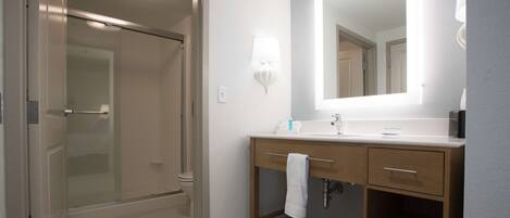 A modern bathroom with a glass shower enclosure, a vanity with a mirror, and a towel rack.