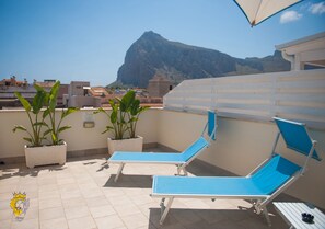 A rooftop terrace with two blue lounge chairs, potted plants, and a view of a mountain. - Accussì rooms (San Vito Lo Capo)