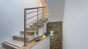 A modern staircase with a metal railing, wooden steps, and a stone wall. - Ayres Del Mar (San Vito Lo Capo)