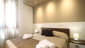 A hotel room with a large bed, two pillows, a nightstand with a lamp, and a window with curtains. - Ayres Del Mar (San Vito Lo Capo)
