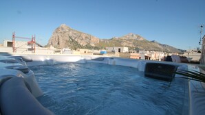 A hot tub with a mountain view, surrounded by buildings and a crane. - Ayres Del Mar (San Vito Lo Capo)