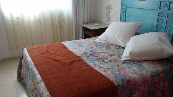 A bed with a floral bedspread, a brown throw blanket, and two white pillows. - Hotel Tulum Iguanas (Tulum)
