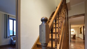 Una escalera de madera con barandilla, que conduce a un comedor con mesa y sillas.