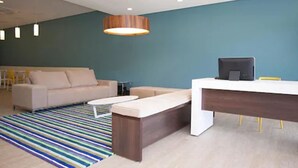 A modern office space with a sofa, a desk, and a striped rug. - Golden Tower Aeroporto - Lizz - By Fênix Hotéis (Uberlandia)