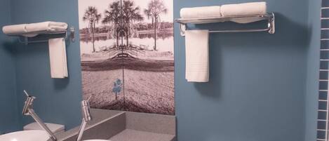 Un baño con pared azul, lavamanos blanco, inodoro y toallero.