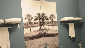 A bathroom with a toilet, a sink, and a mirror. There is a towel rack above the sink and a towel hanging on it.