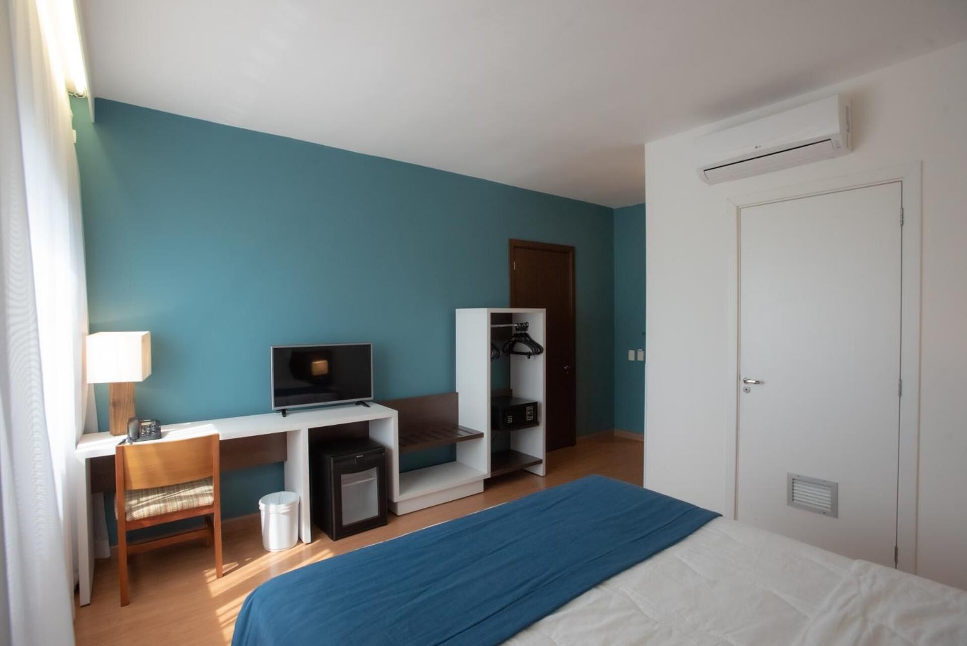 Une chambre d’hôtel comprenant un lit, un bureau avec une télévision, une armoire et une porte.
