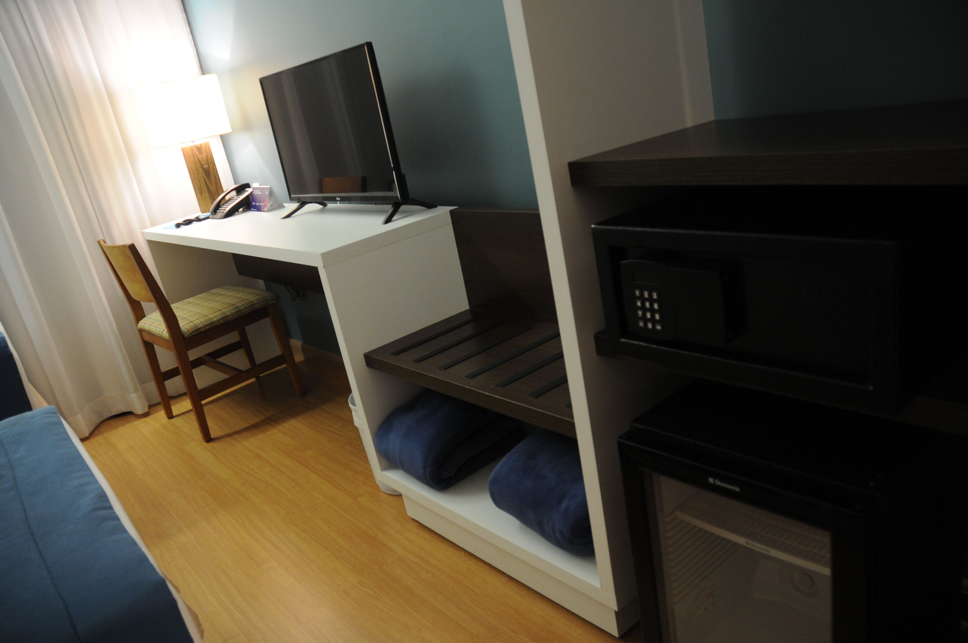 A compact room with a desk, chair, and a microwave.