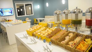 A buffet with various food items and beverages, including bread, pastries, and fruit. - Golden Tower Aeroporto - Lizz - By Fênix Hotéis (Uberlandia)