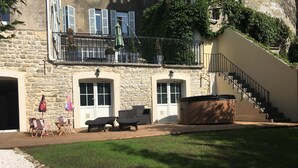 Un bâtiment en pierre doté d’un jacuzzi, d’un espace salon extérieur et d’un escalier.