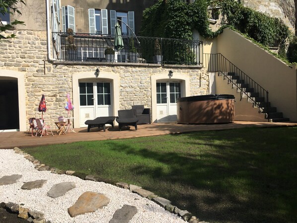 Un edificio de piedra con un jacuzzi, mobiliario de exterior y una escalera.