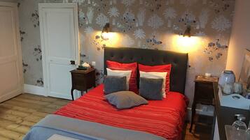 Une chambre à coucher comprenant un lit, des tables de chevet, une commode et une coiffeuse.