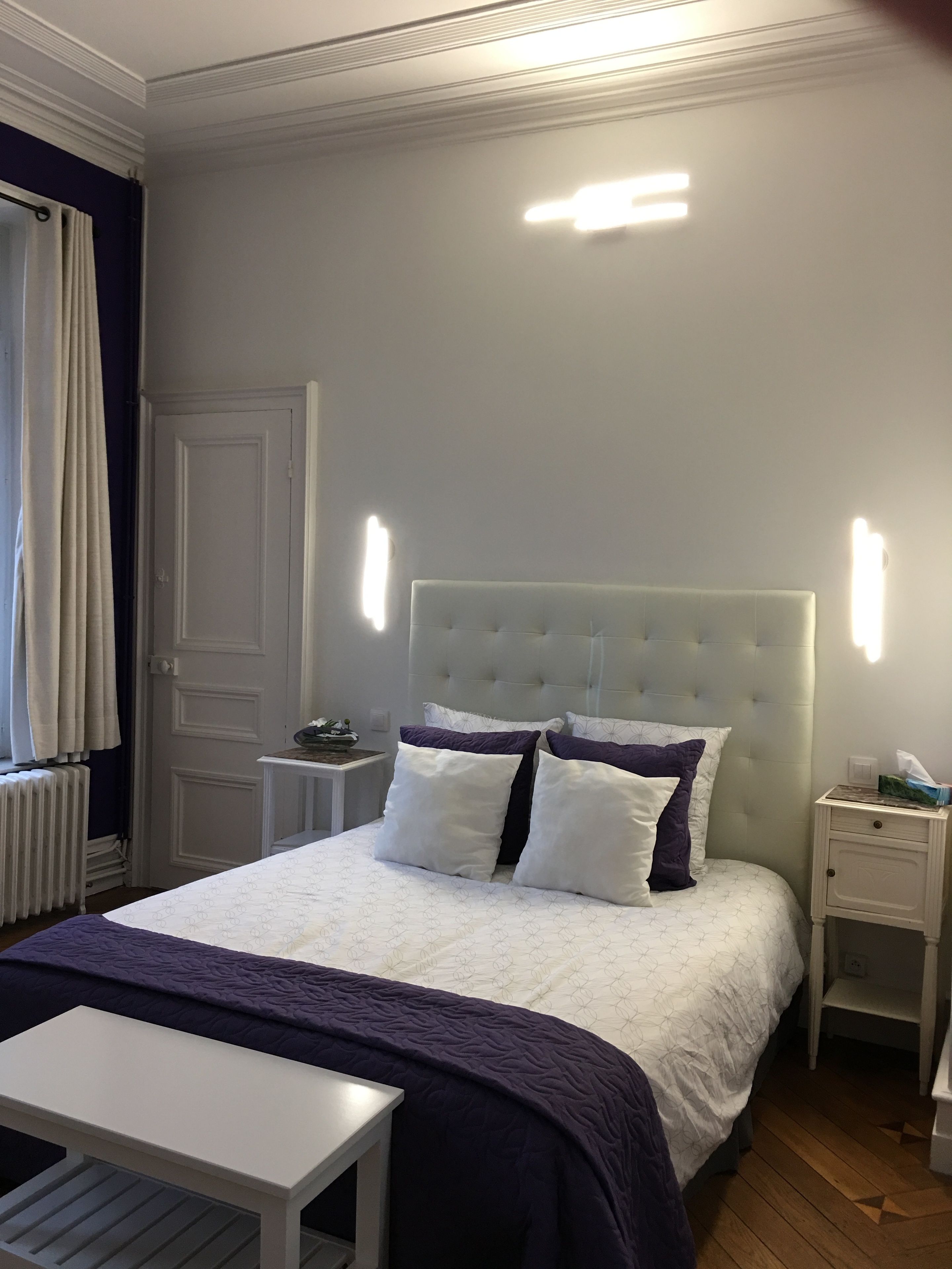 A neatly arranged bedroom with a bed, bedside tables, a nightstand, and a window with curtains.