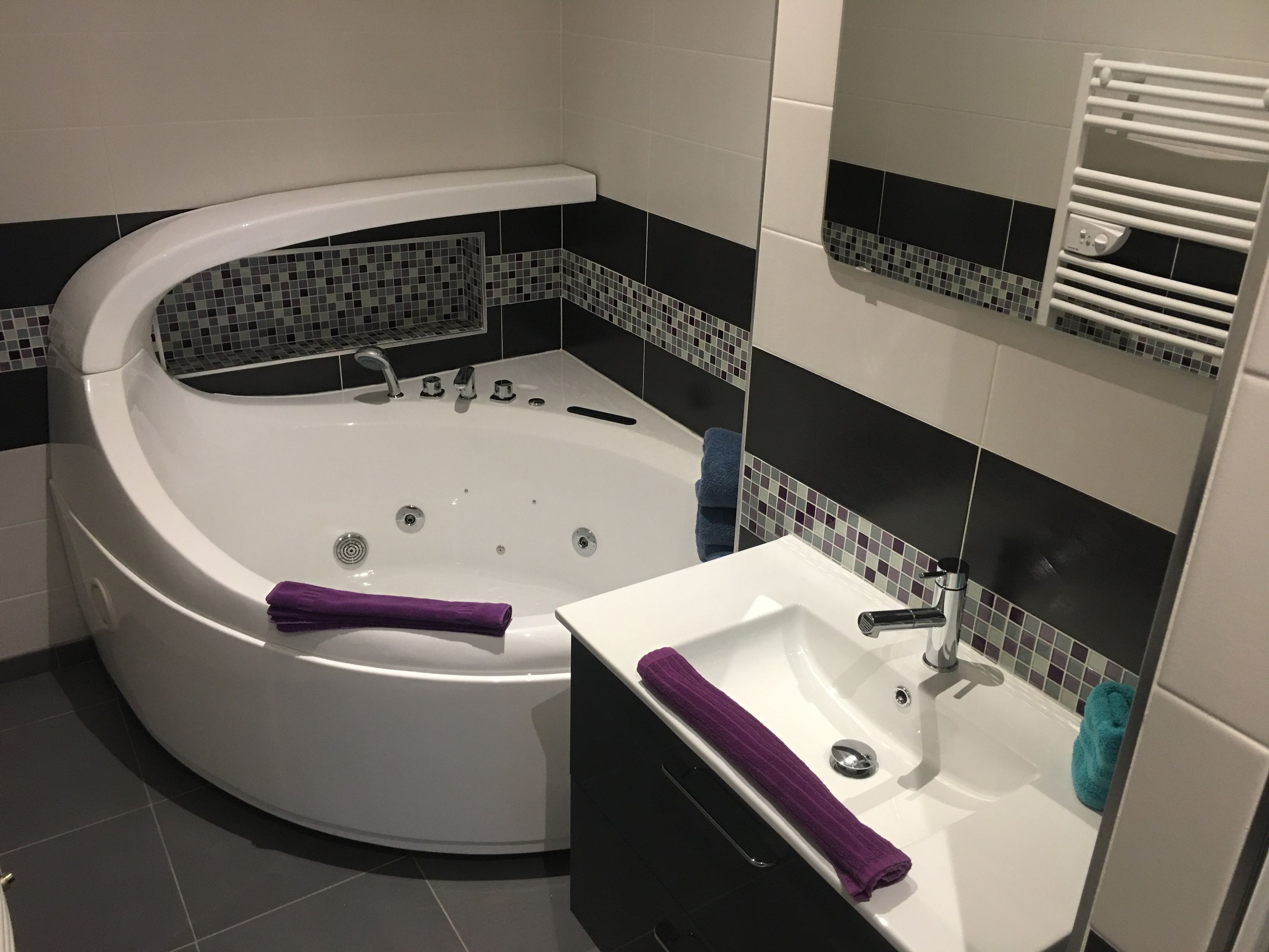 Un baño moderno con una bañera independiente, un lavabo y un perchero para toallas.