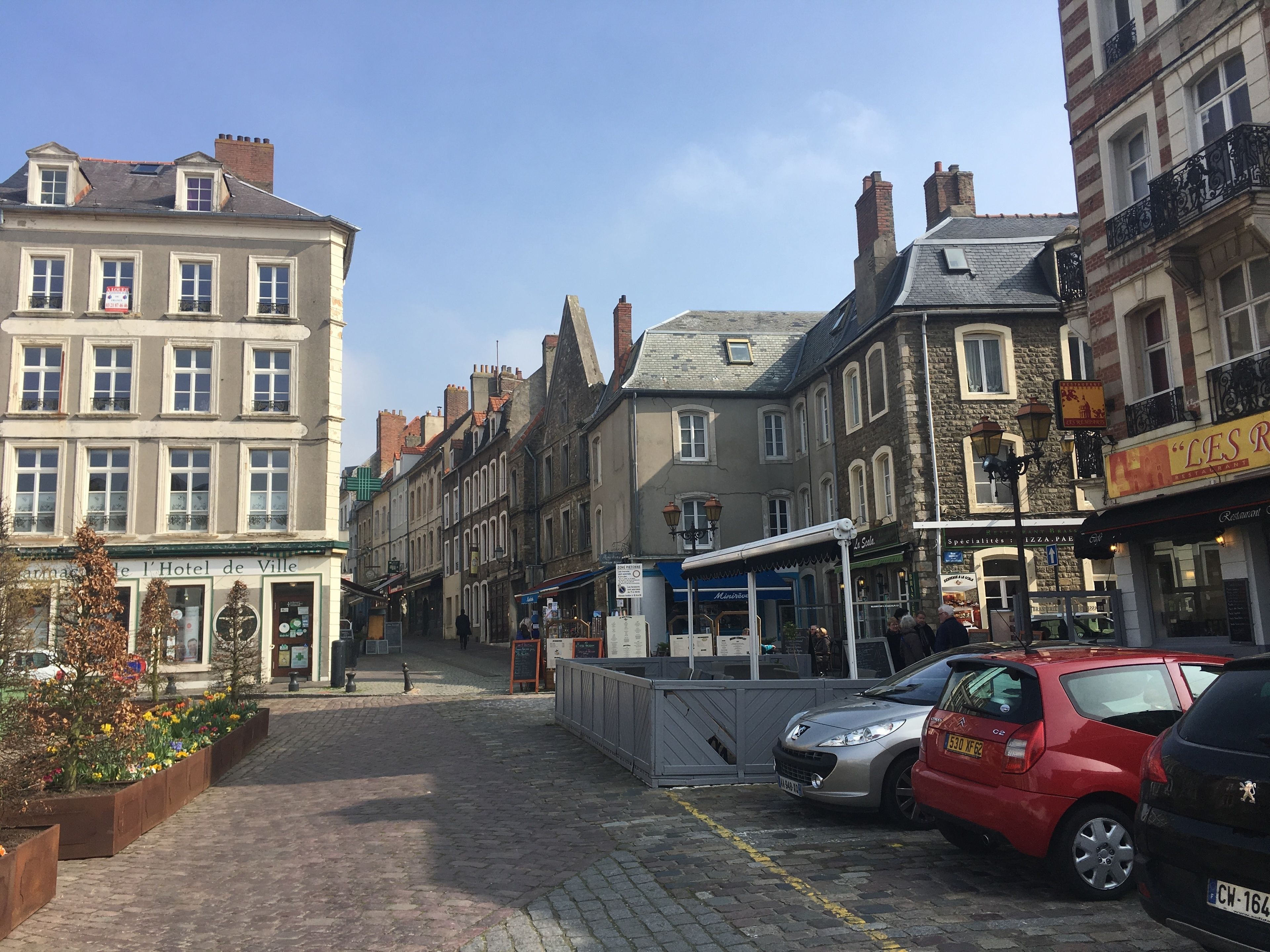 A cobblestone street lined with historic buildings, including a hotel with a sign indicating it is a hotel.
