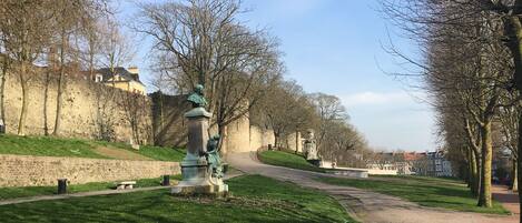 A park with a statue, a stone wall, and a pathway.