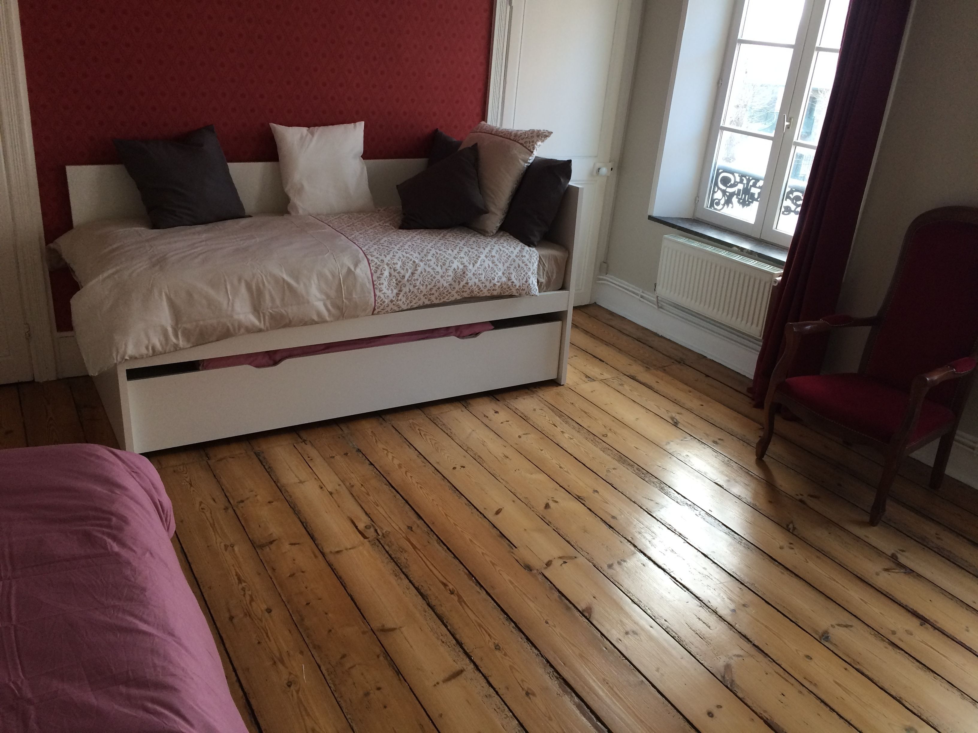 A bedroom with a bed, a chair, and a window.