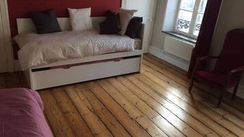 A bedroom with a bed, a chair, and a window.