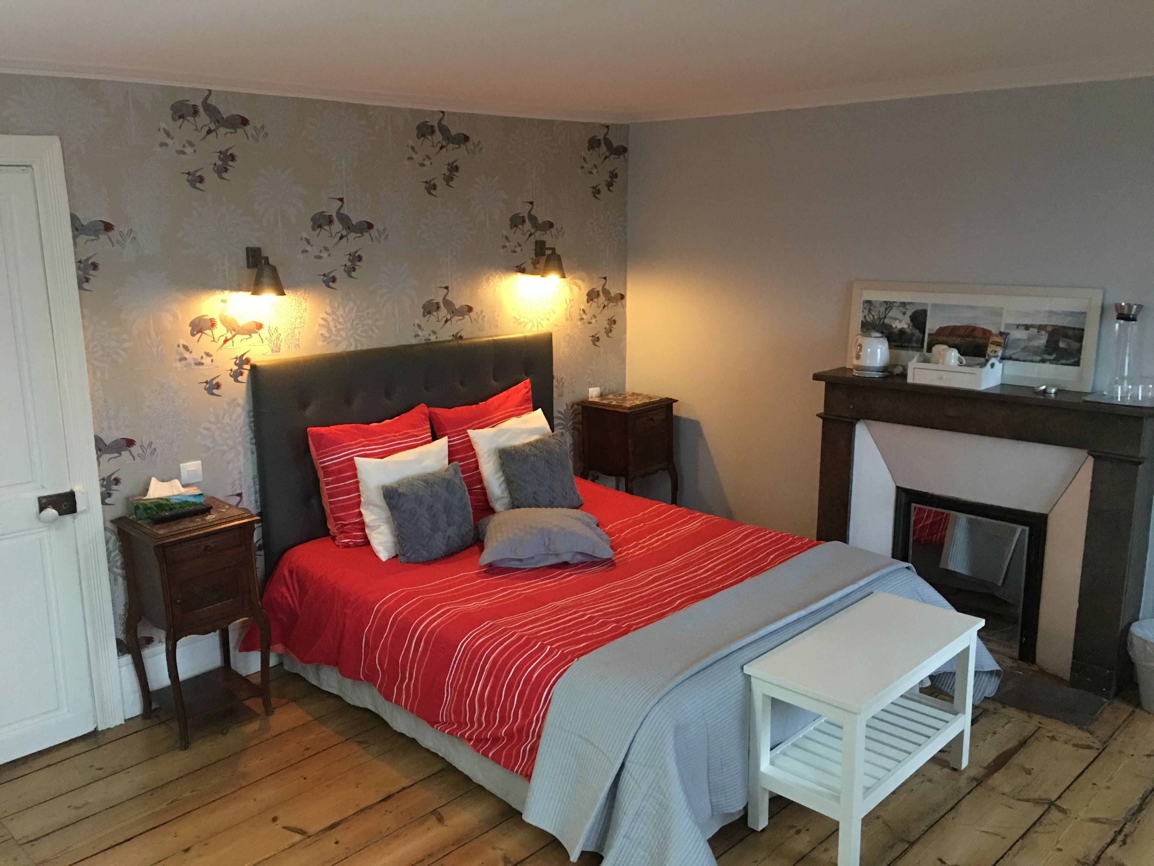 A bedroom with a bed, bedside tables, a nightstand, a fireplace, and a wall with animal decals.