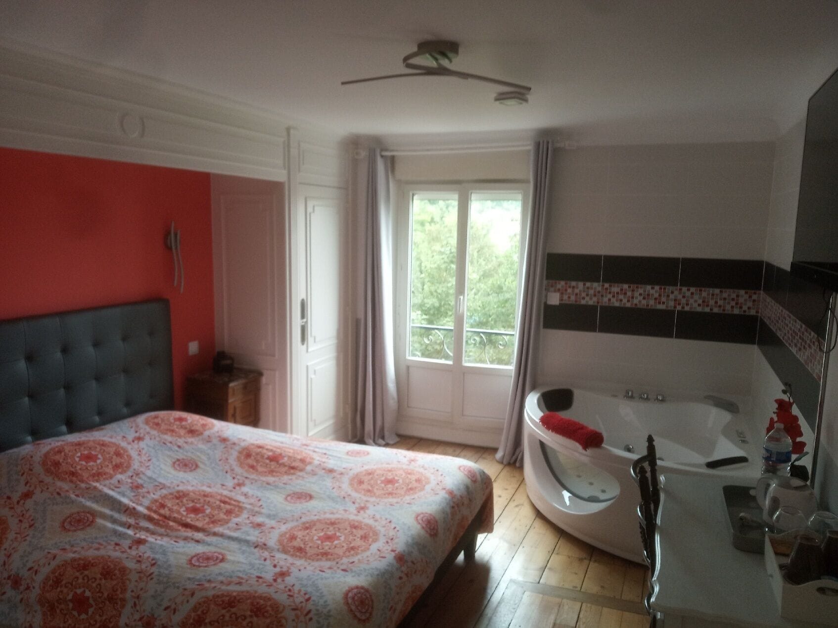 A bedroom with a bed, a window, a bathroom with a bathtub, and a shower.