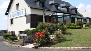 A two-story building with a sign reading "HOTEL DU RELAIS". There are flower beds with red and purple flowers in front of the building. - Contact Hôtel du Relais Thouars (Louzy)