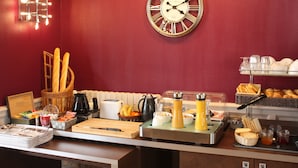 A breakfast buffet with various food items, a clock, and a basket of baguettes. - Contact Hôtel du Relais Thouars (Louzy)