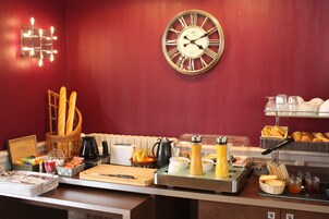 A breakfast buffet with various food items, a clock, and a basket of baguettes.