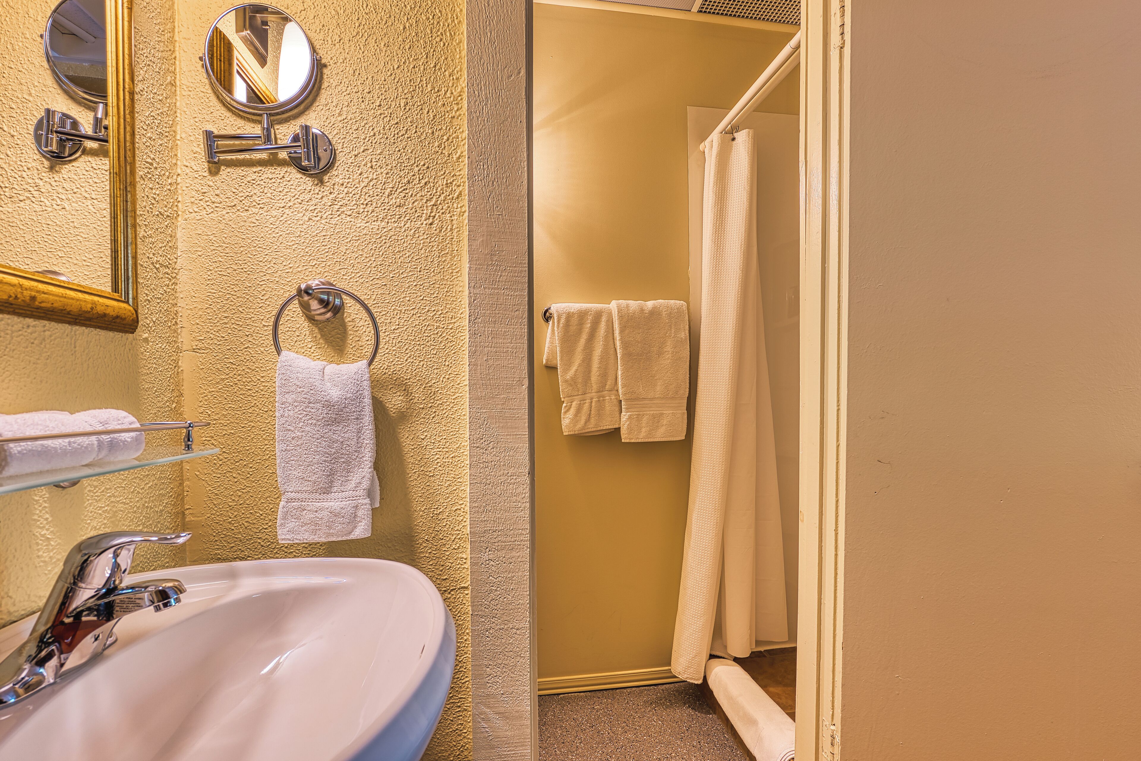 A bathroom with a sink, mirror, towel rack, and shower curtain.