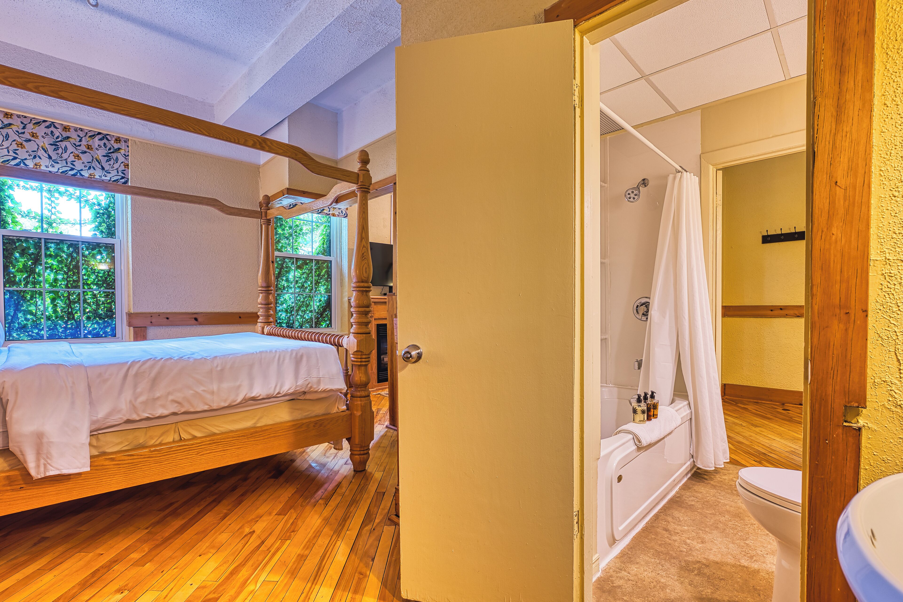 Une chambre avec un lit en bois, une salle de bain avec une baignoire et une douche.