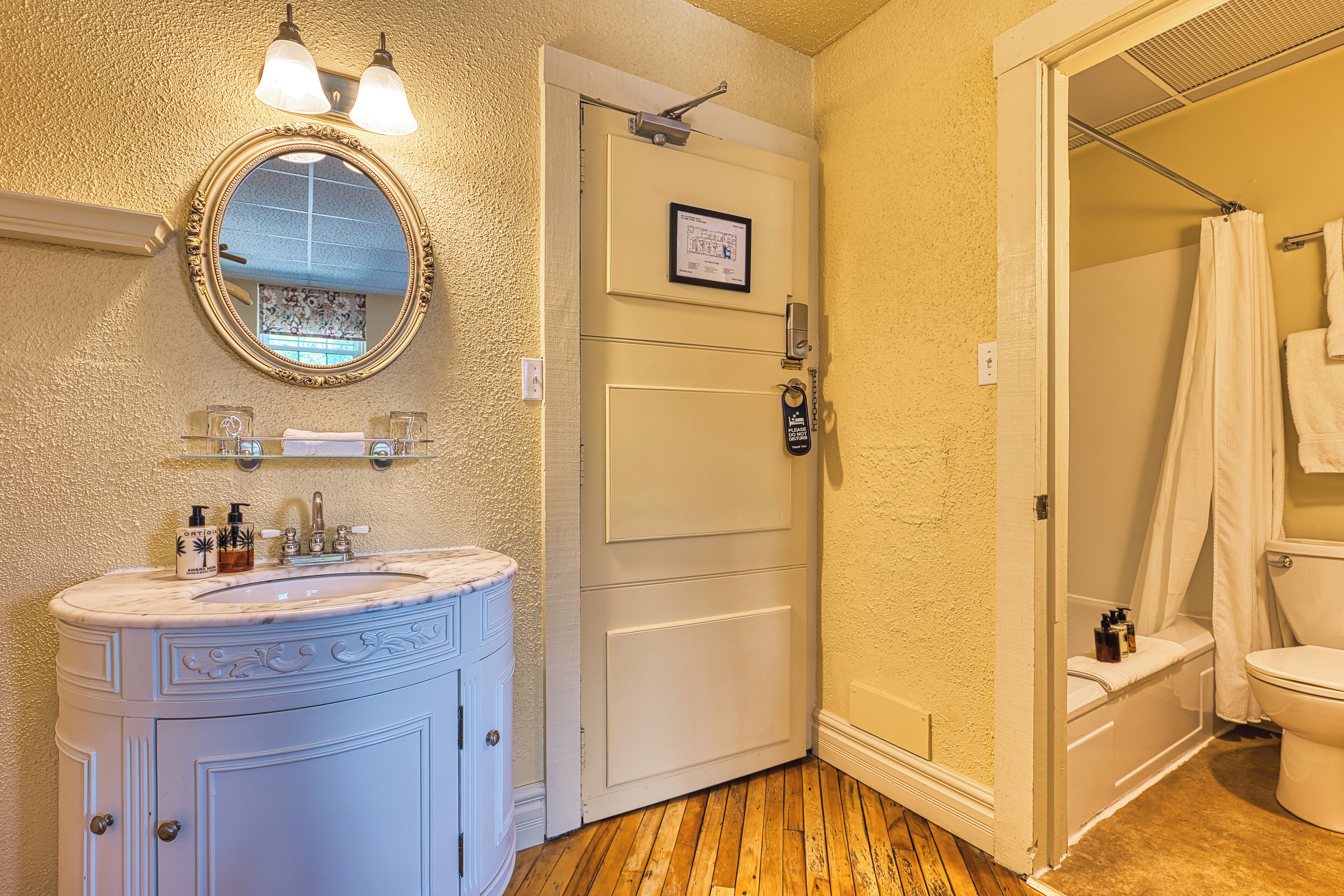A bathroom with a white vanity, a mirror, and a shower area.