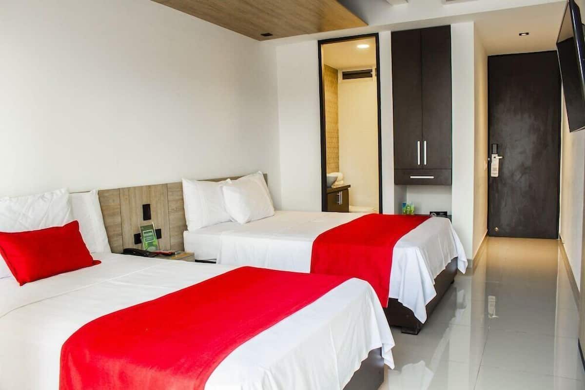 Ein Hotelzimmer mit zwei Betten, einem Kleiderschrank, einem Fernseher und einem durch eine geöffnete Tür einsehbaren Badezimmer.