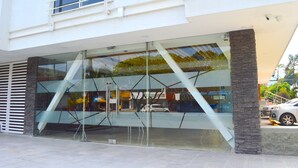 Um edifício moderno com fachada de vidro, uma escadaria e um carro estacionado.