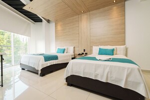 Habitación de hotel con dos camas, techo de madera y un amplio ventanal.