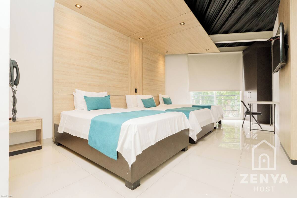 Ein modernes Hotelzimmer mit zwei Betten, einer Holzbalkendecke, einem Flachbildfernseher und einem Fenster mit Blick.