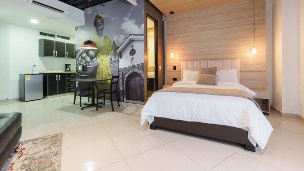Quarto moderno com cama grande, área de refeições e cozinha.