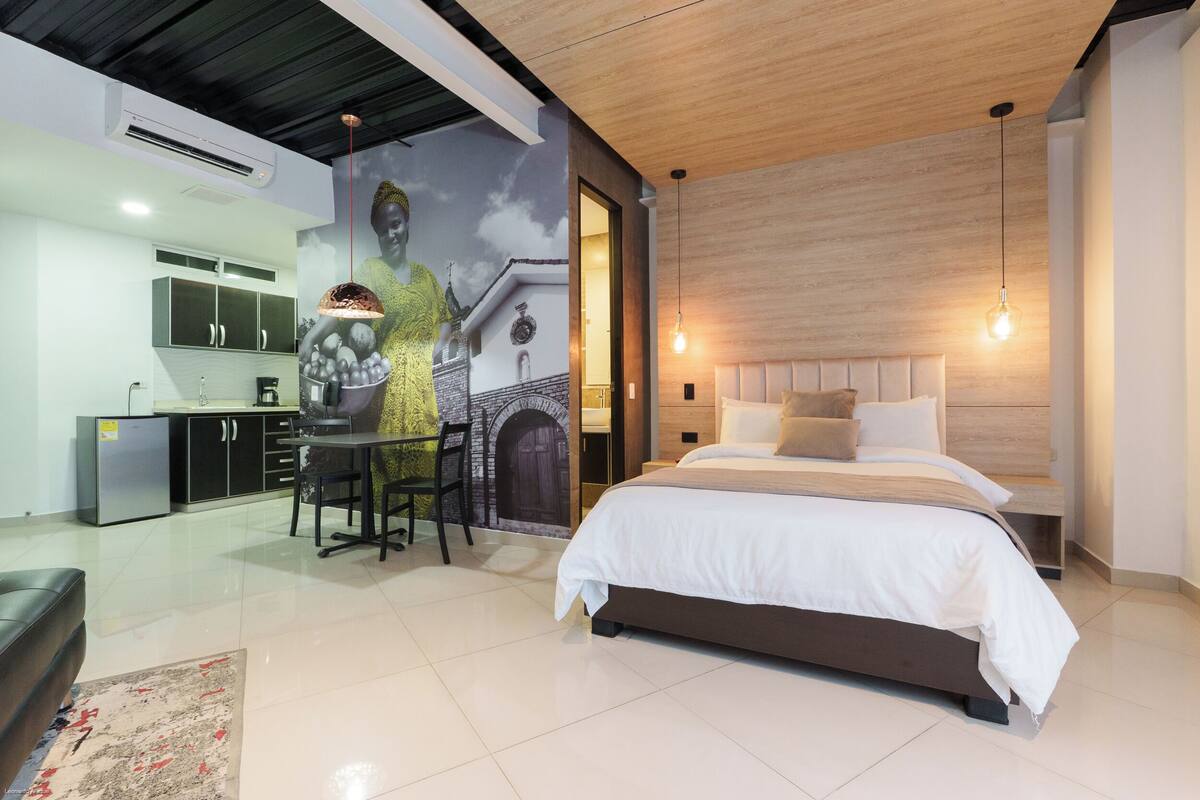 Ein modernes Schlafzimmer mit großem Bett, Essbereich und Küche.
