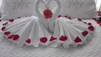 A bed with a white quilt and a decorative swan made of towels.