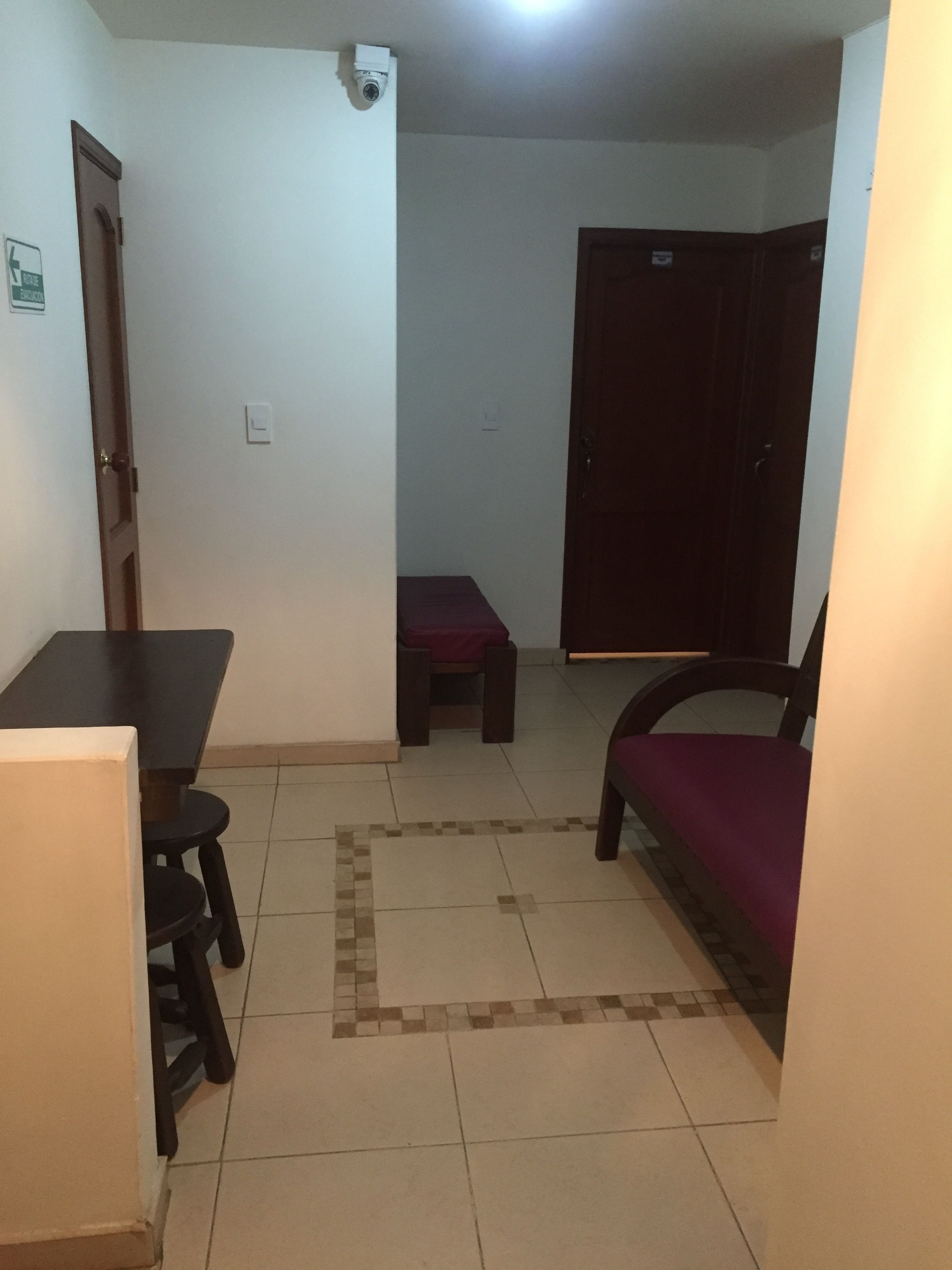A small, dimly lit room with a tiled floor, a wooden table, a bench, and a chair.