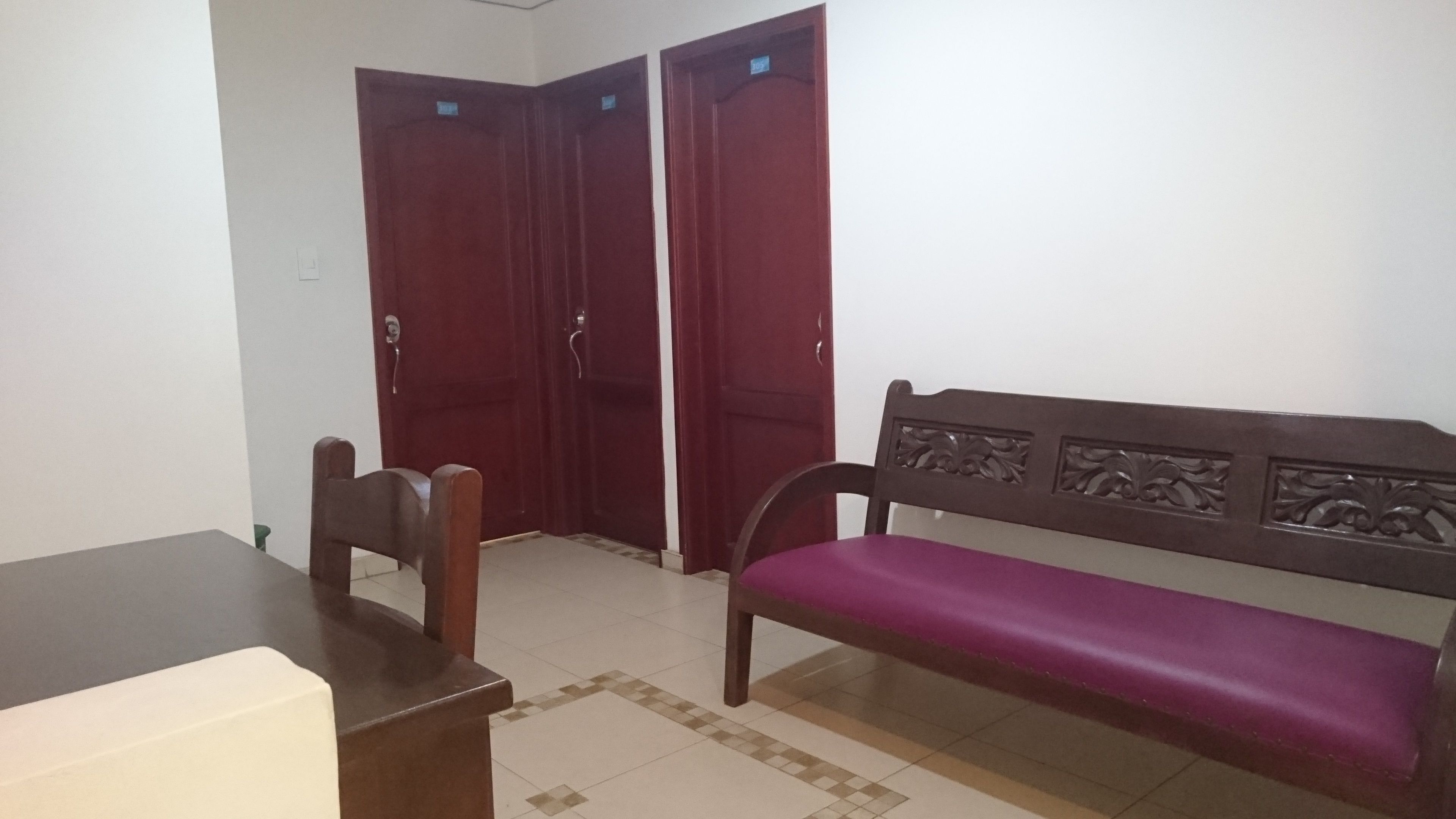 A room with a wooden bench, a table, and two doors.