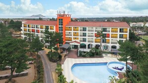 Ein mehrstöckiges Hotel mit Balkonen, einem Schwimmbad und Blick auf das Meer.